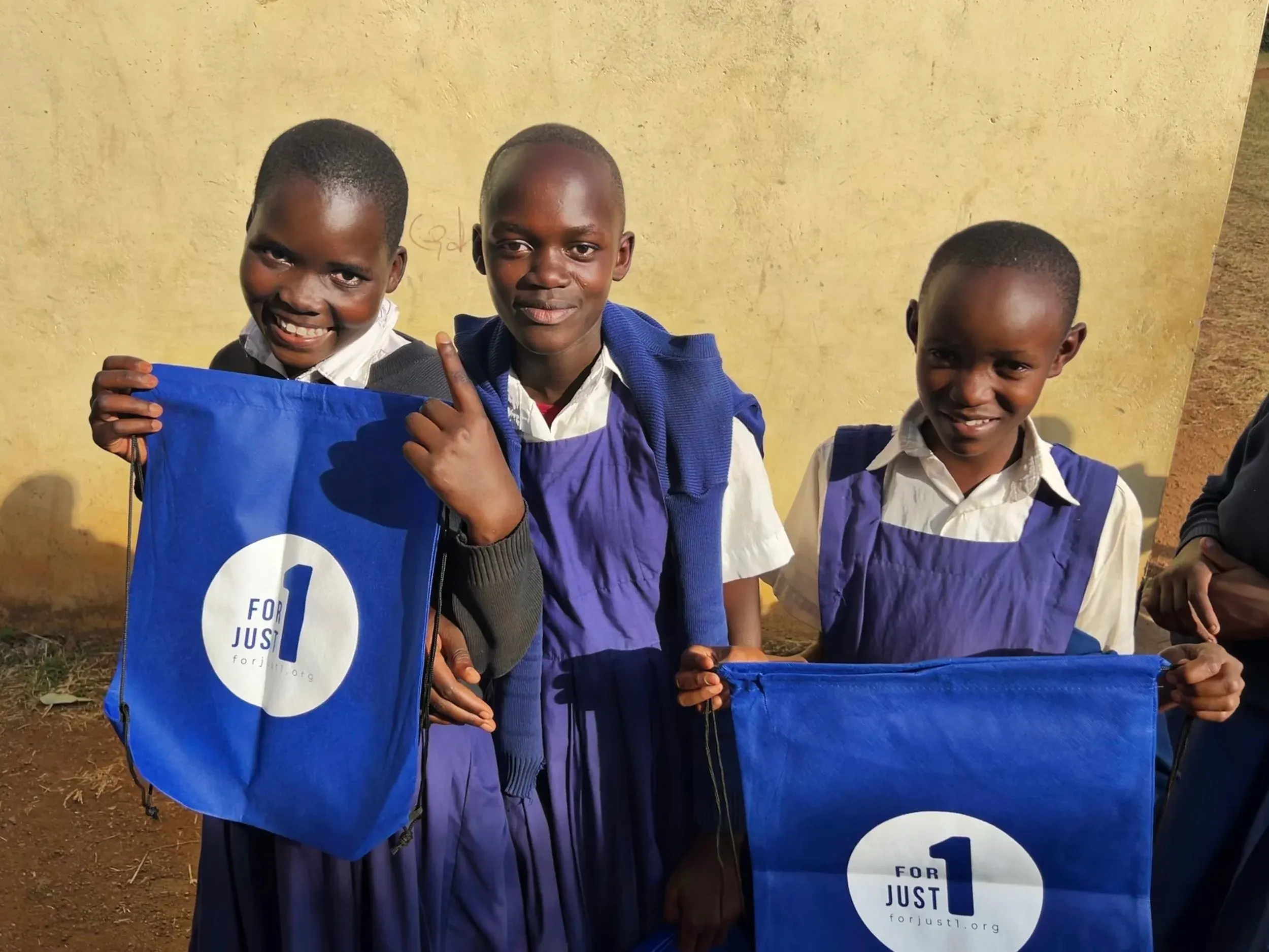 Students in rural Kenya holding For Just 1 school bags — supplies delivered to "the ends of the earth"