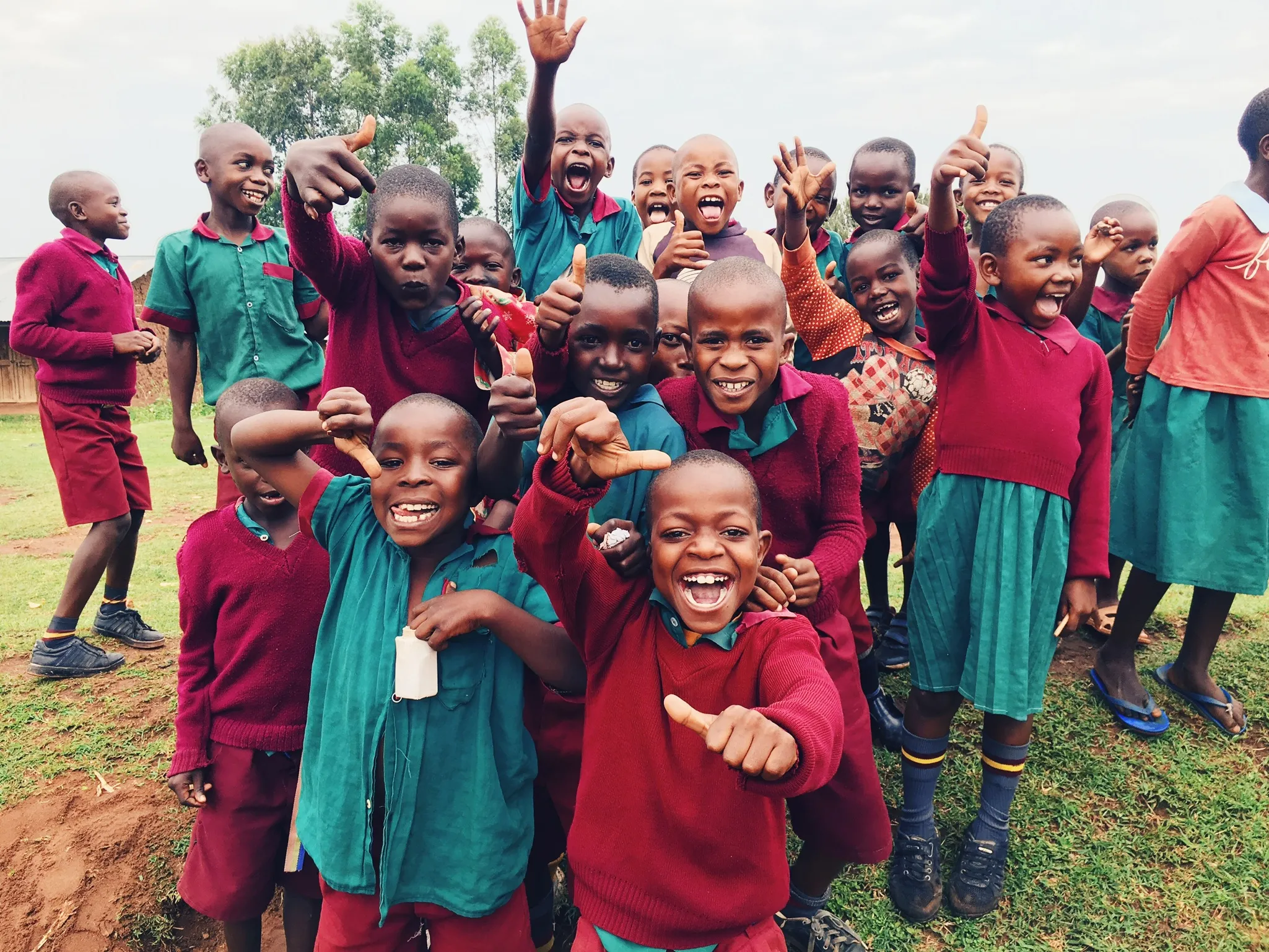 Students in maroon and teal uniforms cheer together during a For Just 1 school visit in rural Kenya